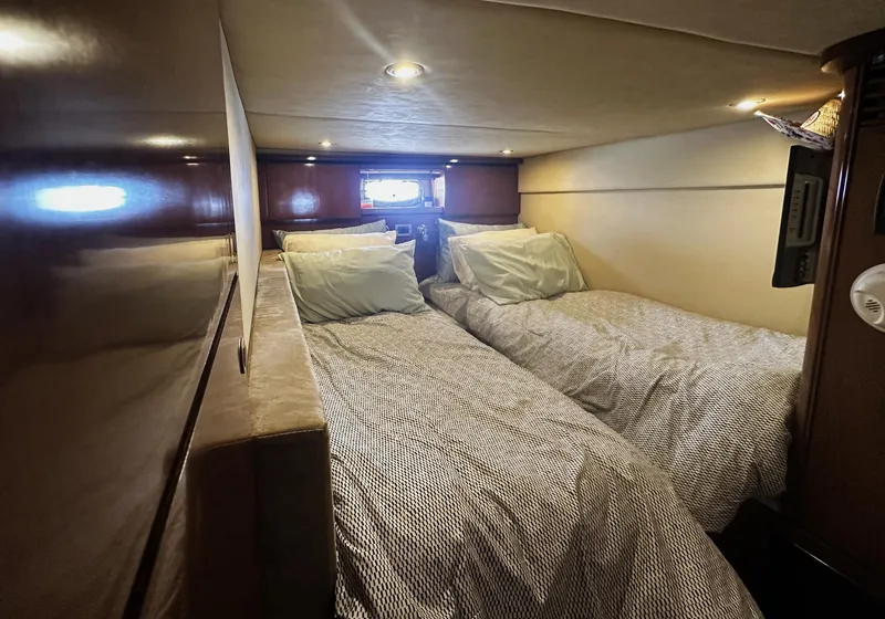 Slide: The Image of 2006 Sea Ray 48 Sundancer cabin with twin beds, cozy lighting, and wooden accents. - 24