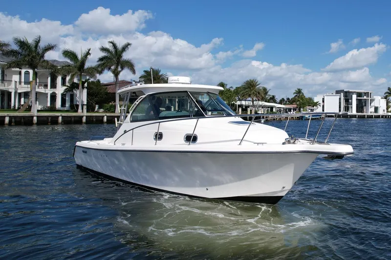 Slide: The Image of 2008 Pursuit 315 Offshore boat cruising on a sunny day near waterfront homes. - 13