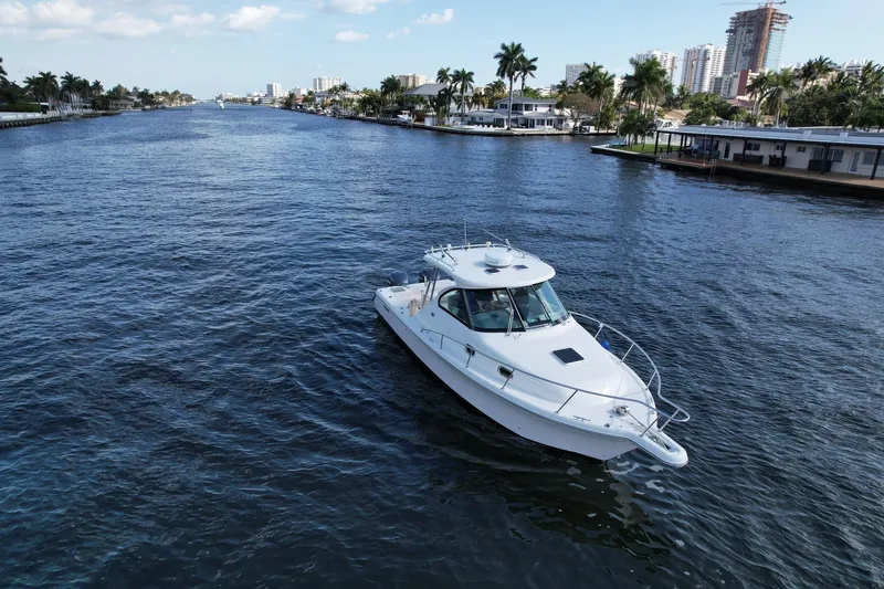 Slide: The Image of 2008 Pursuit 315 Offshore boat cruising on a scenic waterway with palm trees and buildings. - 2