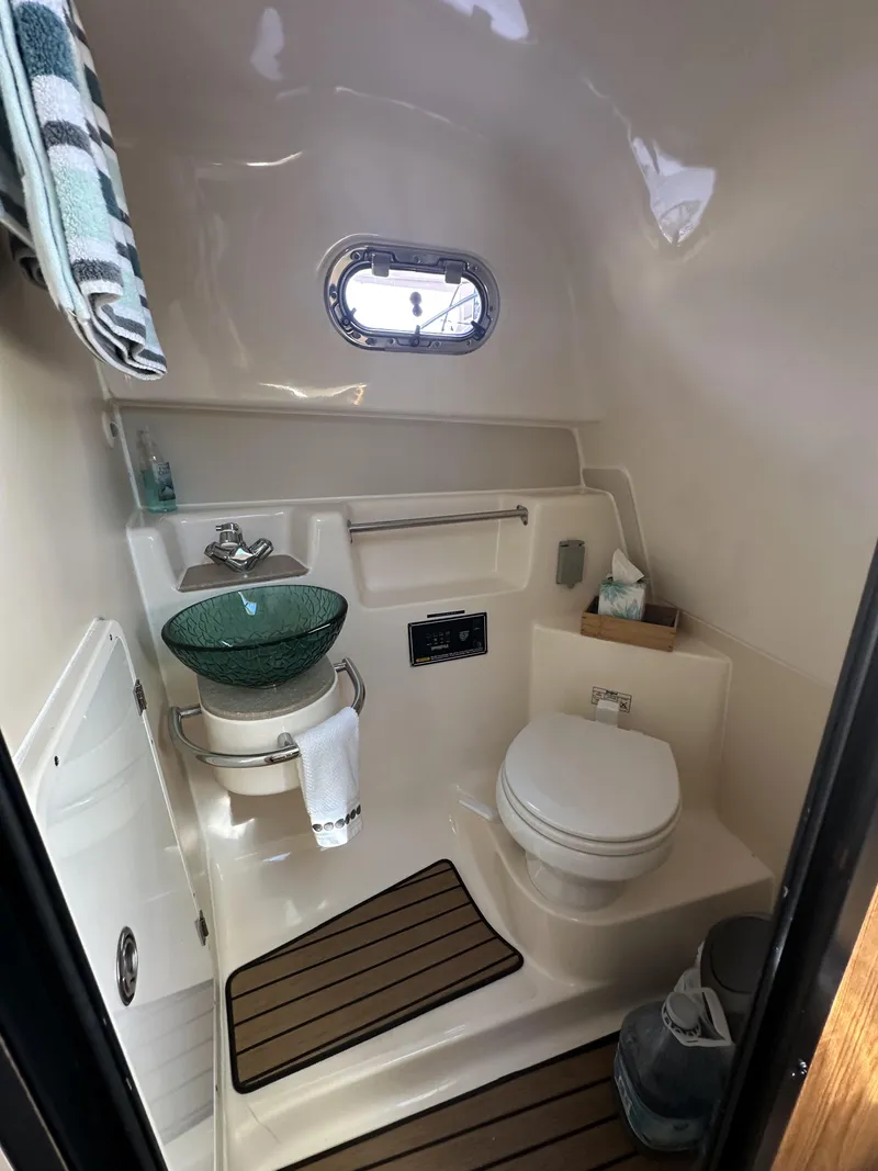 Slide: The Image of 2008 Pursuit 315 Offshore boat bathroom with sink, toilet, and porthole window. - 33