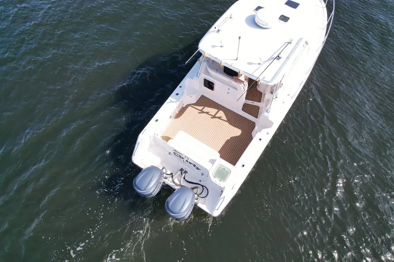 Slide: The Image of 2008 Pursuit 315 Offshore boat on water, aerial view, twin engines visible. - 6