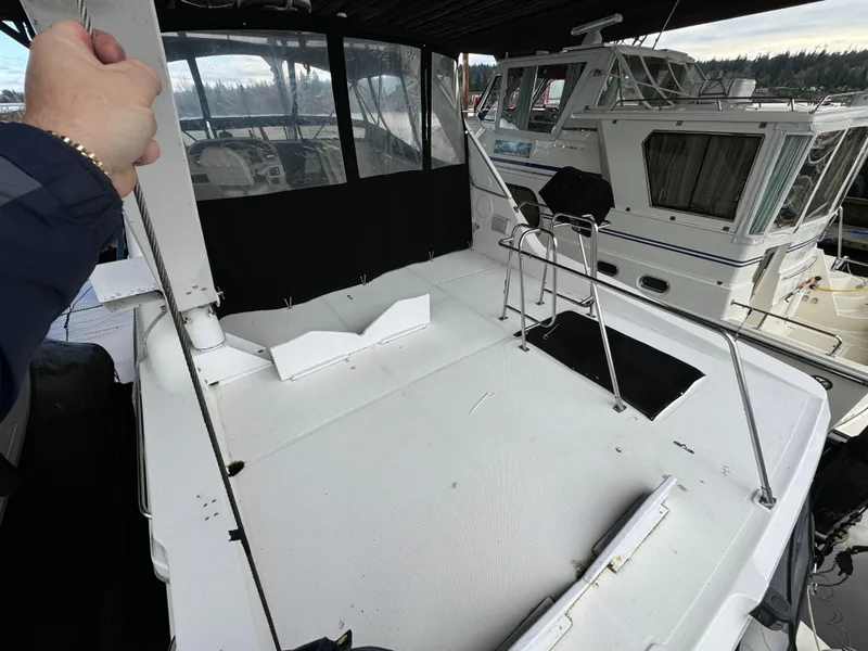 Slide: The Image of 1995 Bayliner 4788 yacht deck with railing and seating, docked alongside another boat. - 12