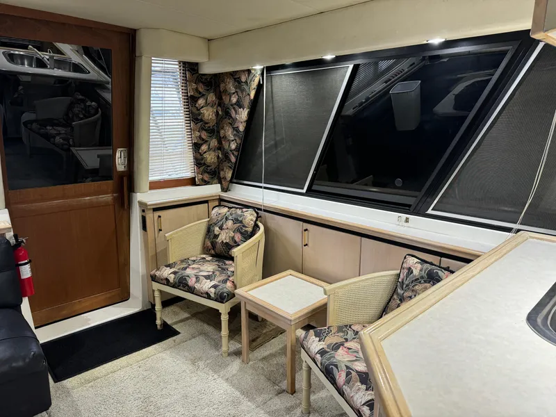 Slide: The Image of Interior of a 1995 Bayliner 4788 yacht with floral chairs and large windows. - 19