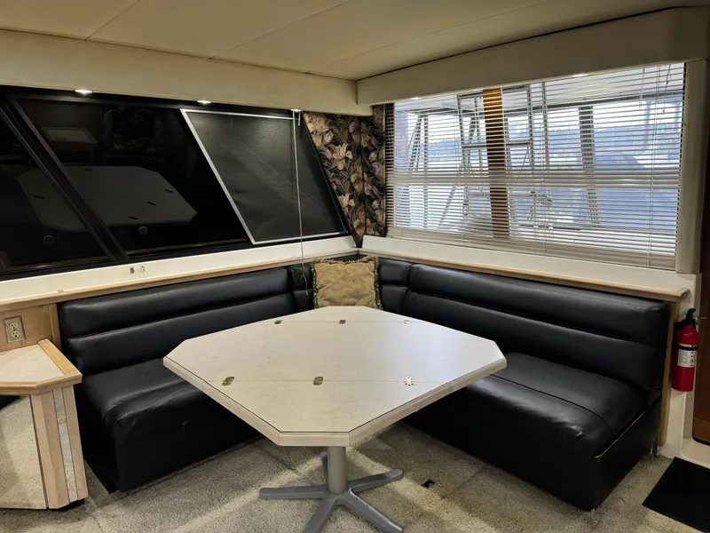 Slide: The Image of Interior of 1995 Bayliner 4788 yacht with black leather seating and hexagonal table. - 21