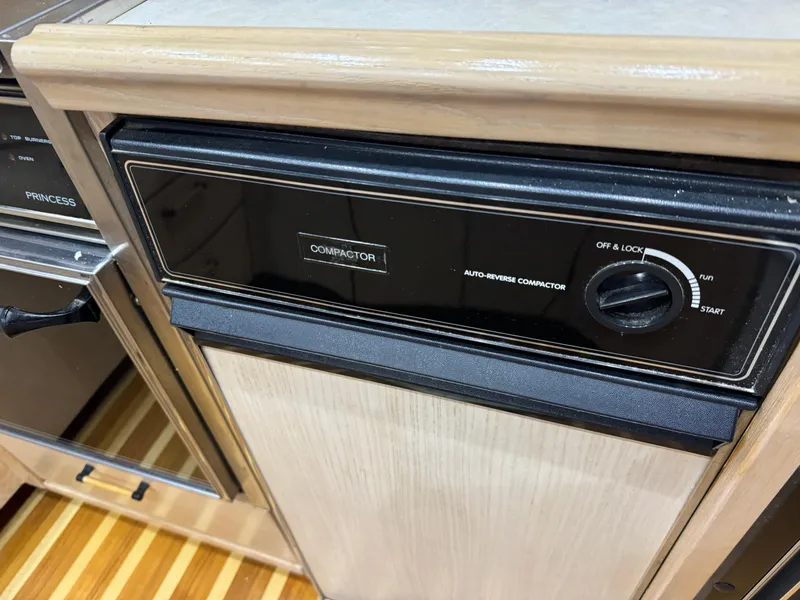 Slide: The Image of 1995 Bayliner 4788 kitchen with auto-reverse compactor and wooden cabinetry. - 26