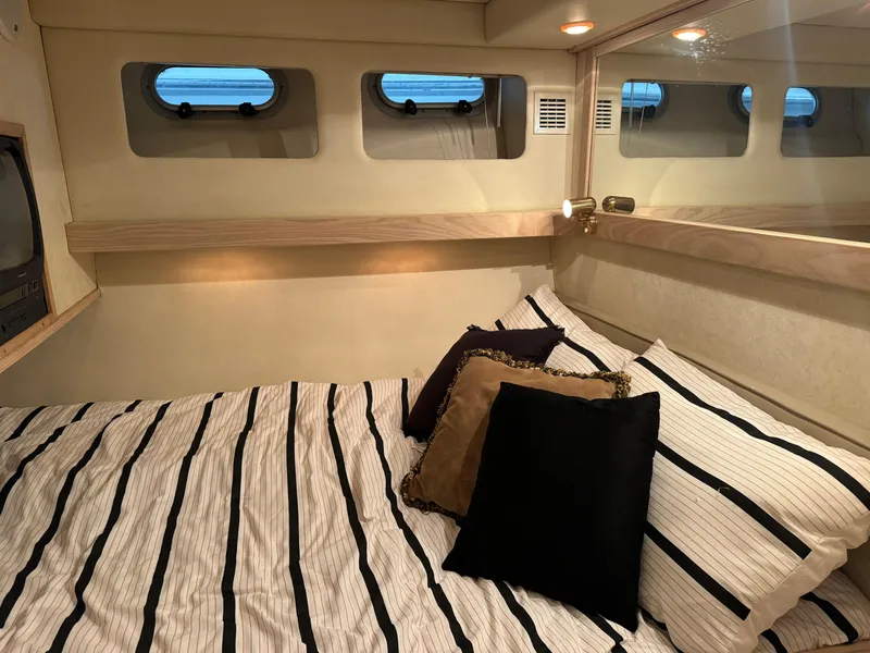 Slide: The Image of Cozy bedroom interior of 1995 Bayliner 4788 yacht with striped bedding and decorative pillows. - 29