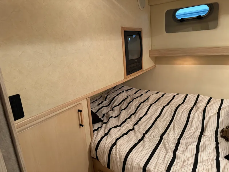 Slide: The Image of Cozy cabin interior of 1995 Bayliner 4788 with striped bedding and built-in TV. - 30