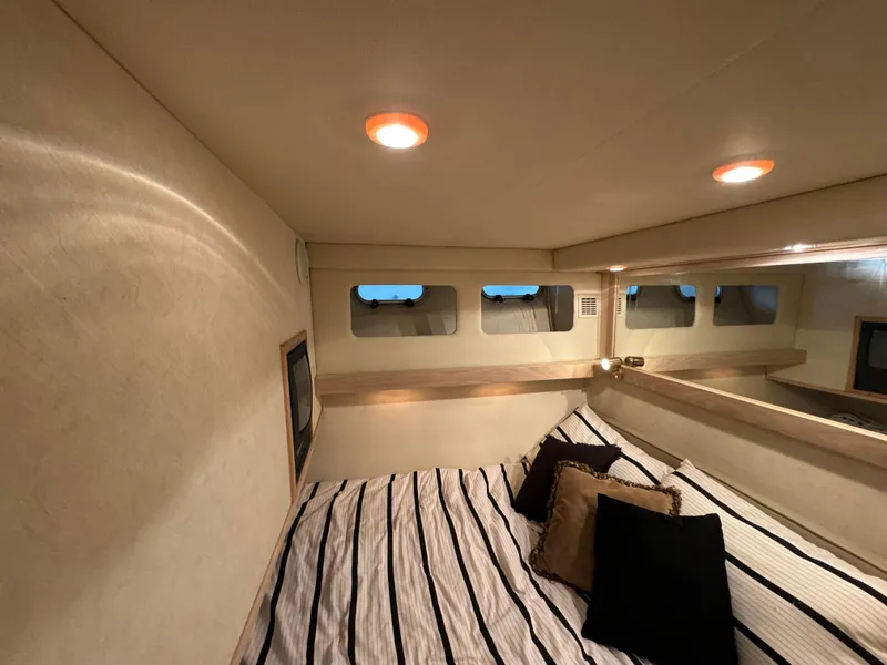 Slide: The Image of Cozy cabin interior of 1995 Bayliner 4788 yacht with striped bedding and ambient lighting. - 32