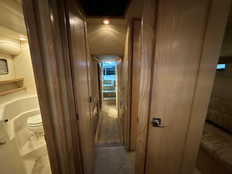 Slide: The Image of Interior hallway of a 1995 Bayliner 4788 yacht, featuring wood paneling and a bathroom. - 38
