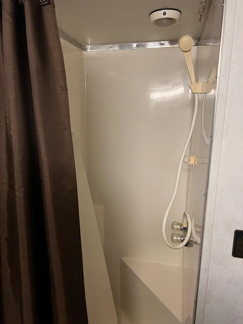 Slide: The Image of Shower area in a 1996 Gibson 41 Sunsport boat with brown curtain and handheld showerhead. - 14