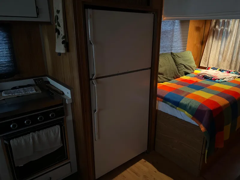 Slide: The Image of Interior of a 1996 Gibson 41 Sunsport with kitchen and colorful bedspread. - 19