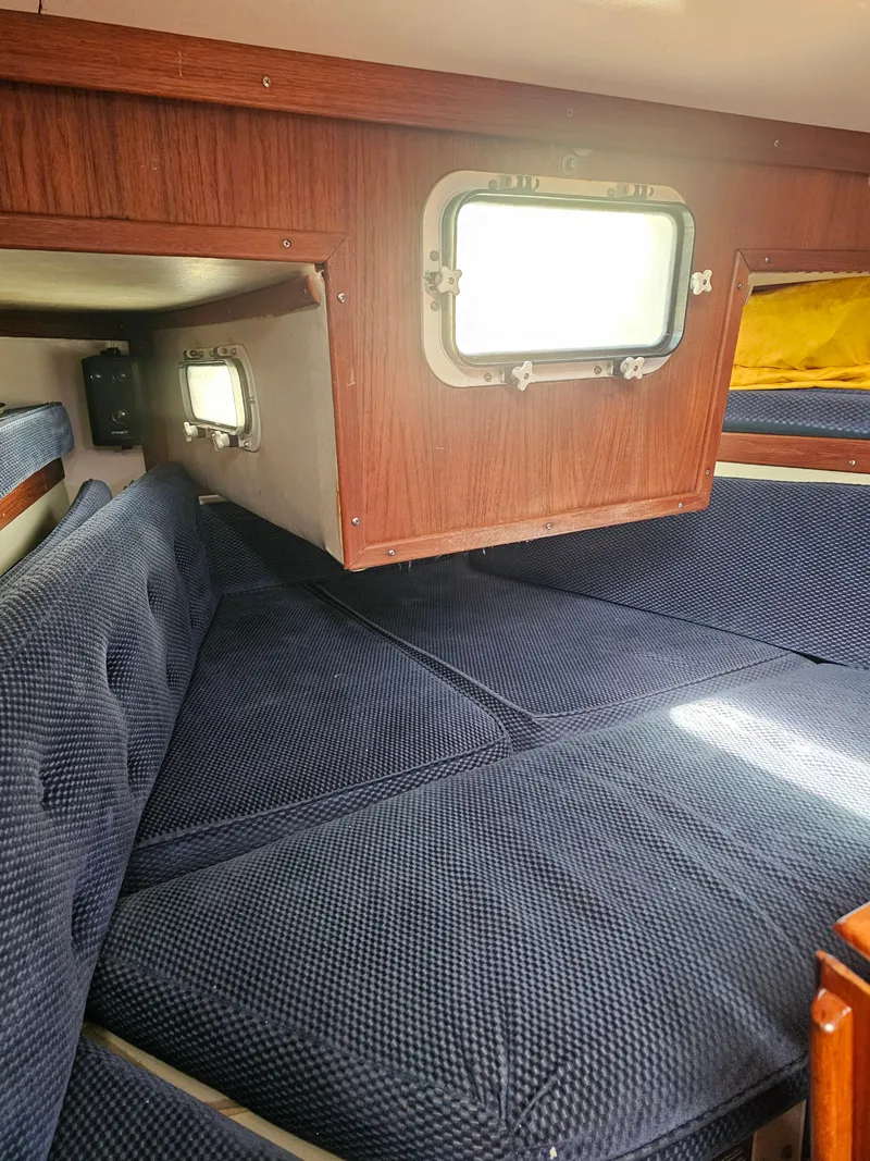 Slide: The Image of Cozy cabin interior of 1984 Schock NY 36 sailboat with blue cushions and wooden accents. - 37