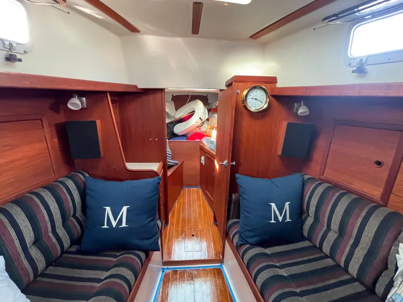 Slide: The Image of 1980 Hinterhoeller Niagra sailboat interior with striped seating, wooden finish, and nautical decor. - 15
