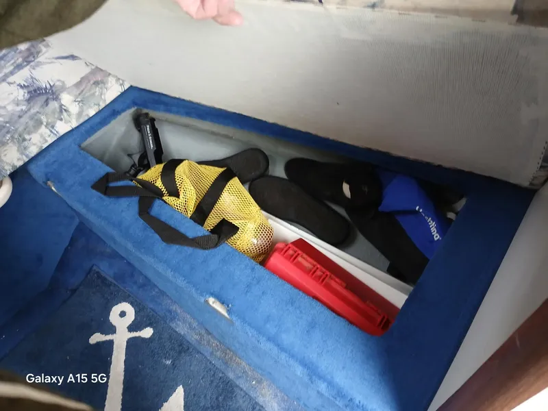 Slide: The Image of Storage compartment in a 1997 Sea Ray 240 Sundancer boat with various items. - 22