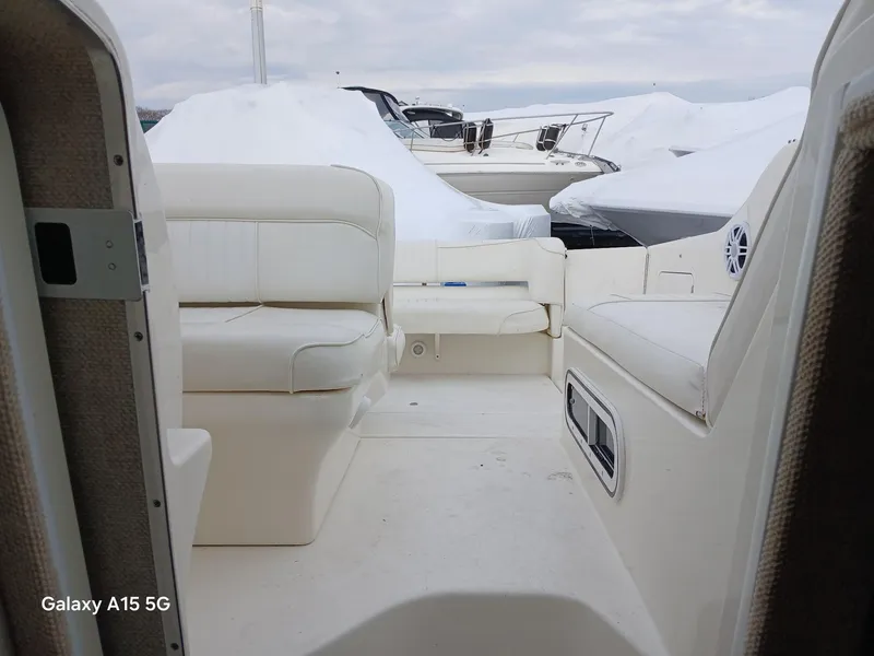 Slide: The Image of 1997 Sea Ray 240 Sundancer boat interior with white seating, docked near covered boats. - 30