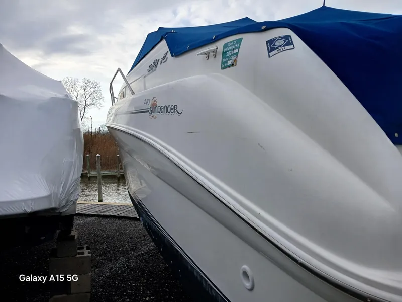 The Image of 1997 Sea Ray 240 Sundancer boat with blue cover, docked near water. - 6