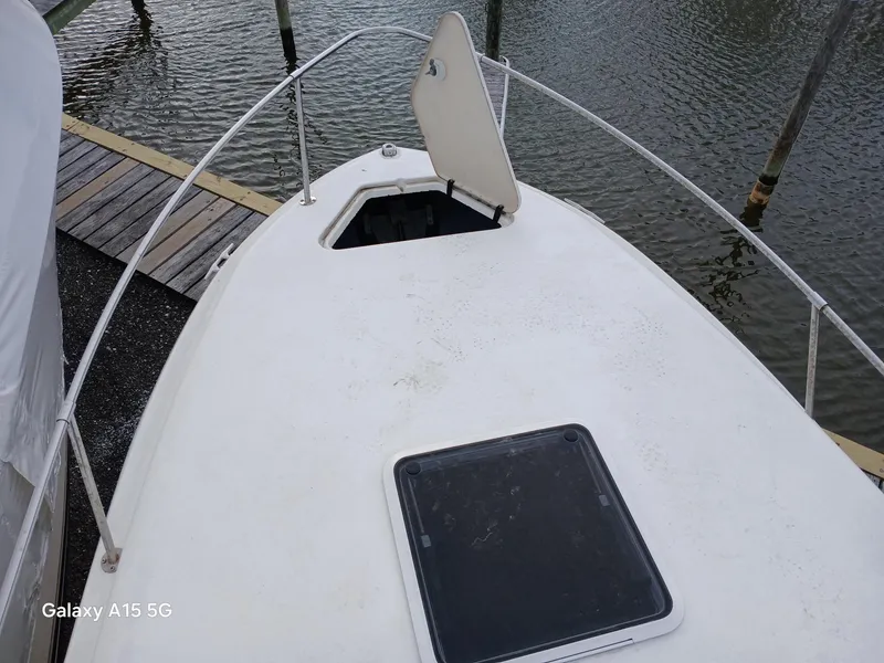 Slide: The Image of 1997 Sea Ray 240 Sundancer boat deck with open hatch, docked by the water. - 33