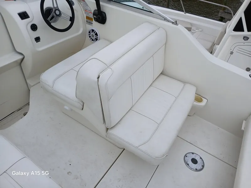 Slide: The Image of 1997 Sea Ray 240 Sundancer boat interior with white seating and steering wheel. - 15