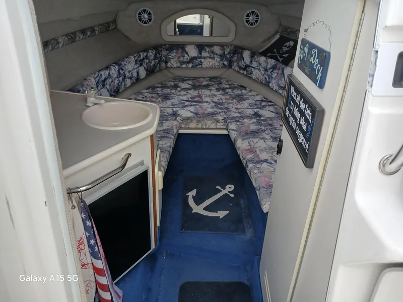 Slide: The Image of Interior of a 1997 Sea Ray 240 Sundancer boat with floral upholstery and compact amenities. - 19