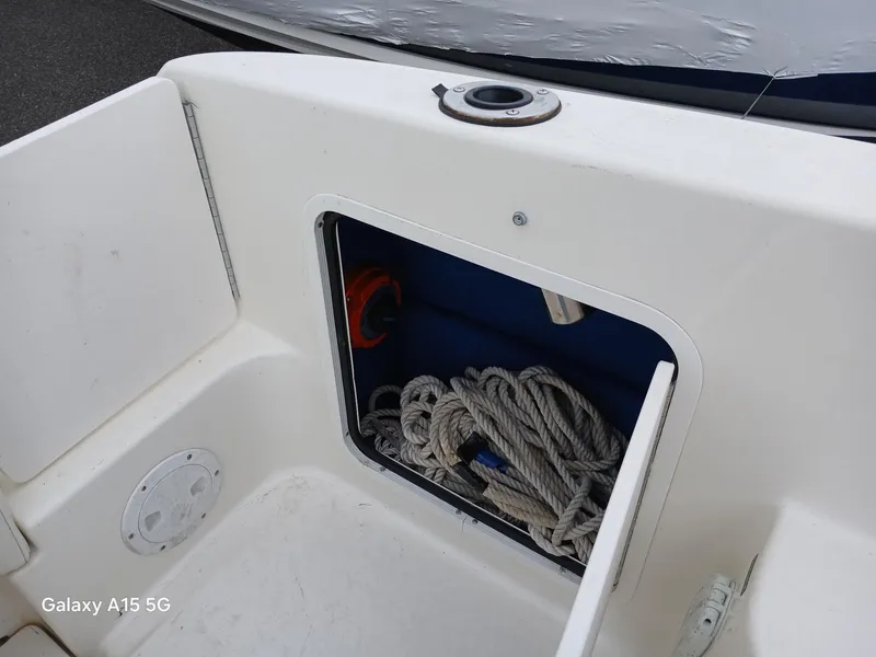 Slide: The Image of 1997 Sea Ray 240 Sundancer storage compartment with rope and equipment. - 14