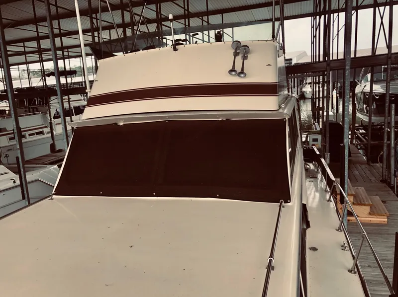 Slide: The Image of 1985 Marinette 32 Sedan Flybridge in marina, front view under covered dock. - 18