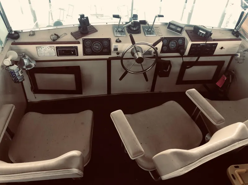 Slide: The Image of 1985 Marinette 32 Sedan Flybridge helm with dual seats, steering wheel, and control panel. - 19