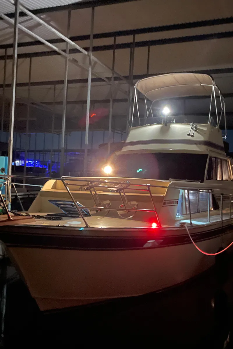 Slide: The Image of 1985 Marinette 32 Sedan Flybridge docked in a covered marina at night. - 2