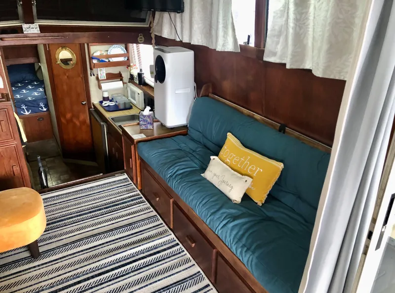 Slide: The Image of 1985 Marinette 32 Sedan Flybridge interior with cozy seating, striped rug, and nautical decor. - 23