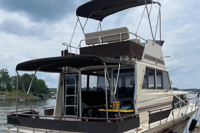 Slide: The Image of 1985 Marinette 32 Sedan Flybridge boat on a calm lake under cloudy skies. - 3