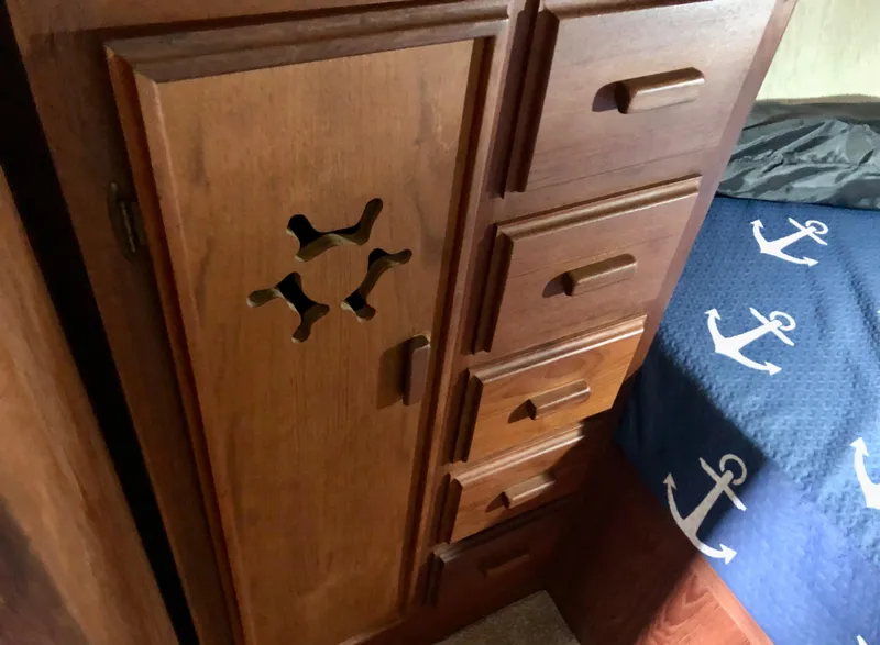 Slide: The Image of Wooden cabinetry and anchor-themed bedding in a 1985 Marinette 32 Sedan Flybridge interior. - 30