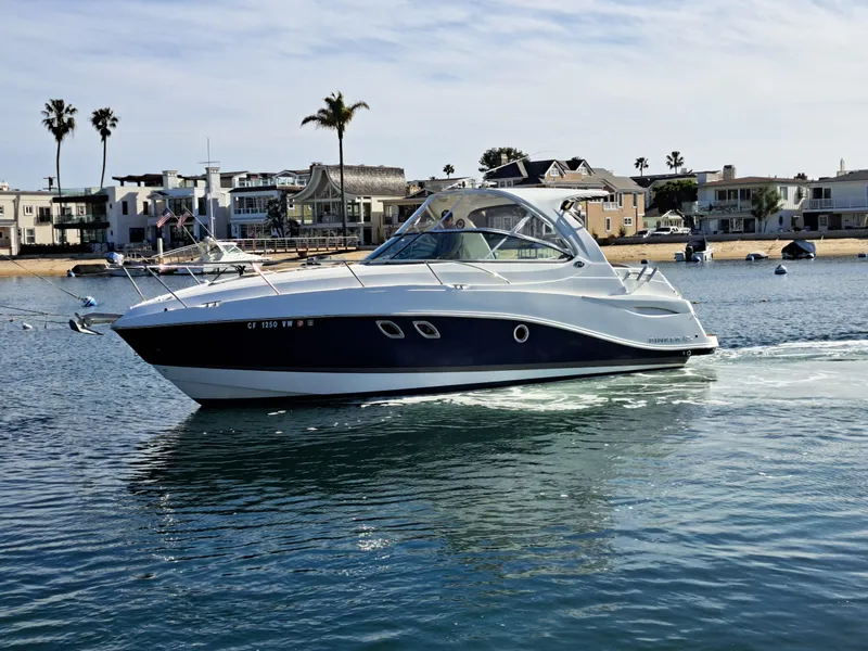 Slide: The Image of 2013 Rinker 310 Express Cruiser on calm water near coastal homes. - 1