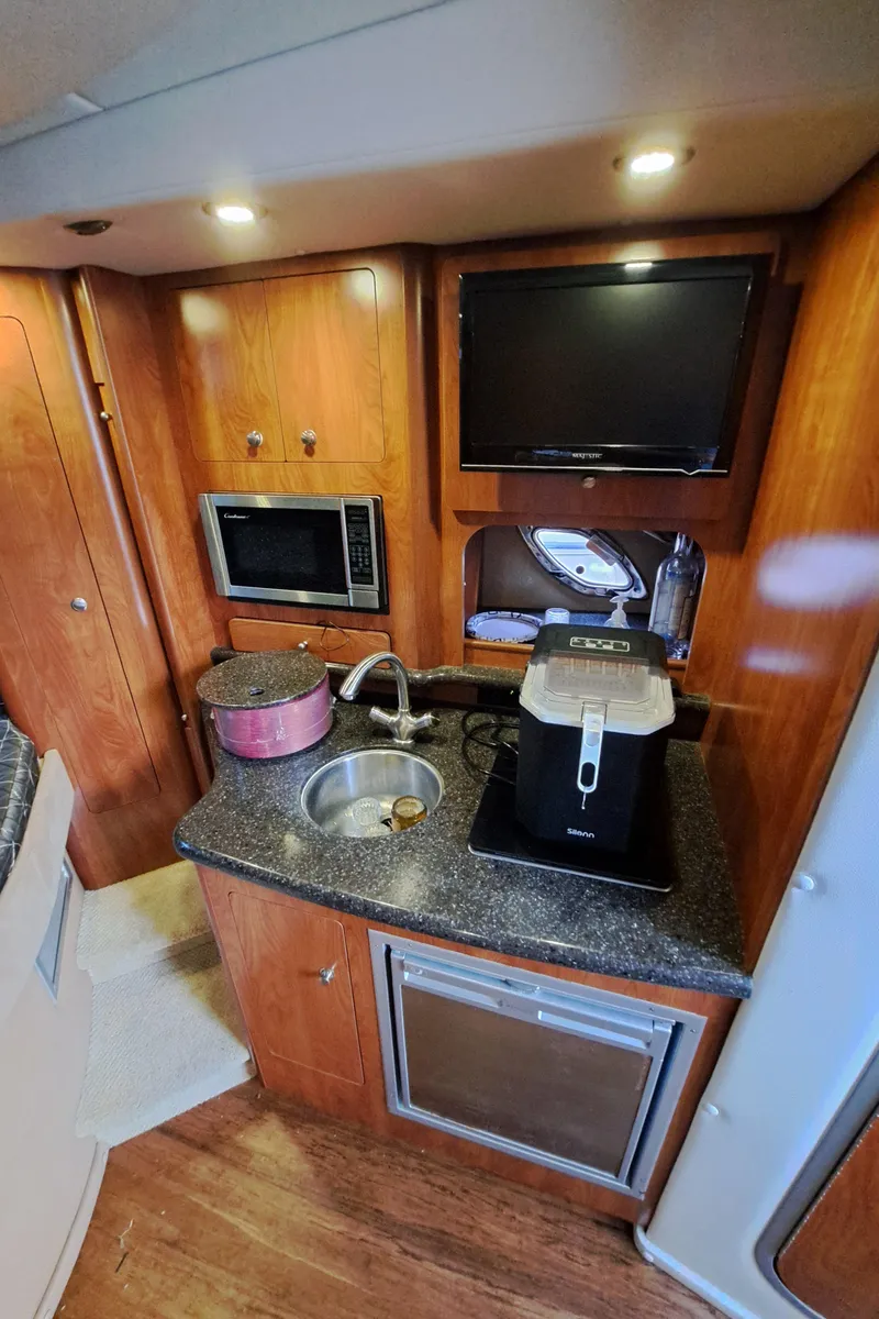 Slide: The Image of 2013 Rinker 310 Express Cruiser kitchen area with microwave and coffee maker. - 13