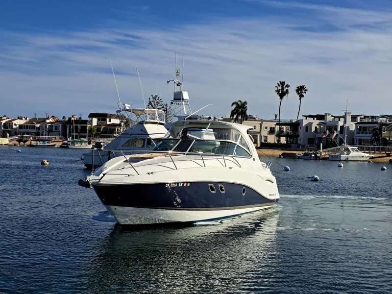 Slide: The Image of 2013 Rinker 310 Express Cruiser on calm water near coastal homes. - 3