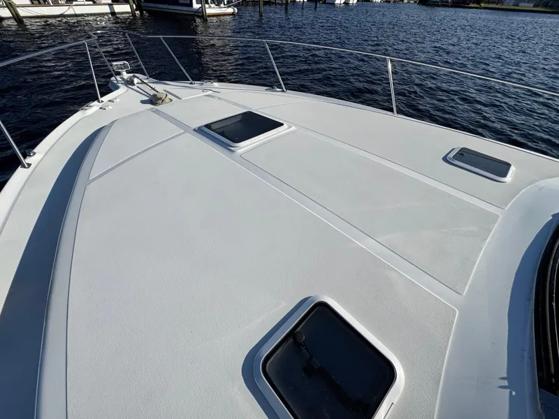 Slide: The Image of 1997 Sea Ray 370 Express Cruiser deck view with hatches, docked on calm water. - 45