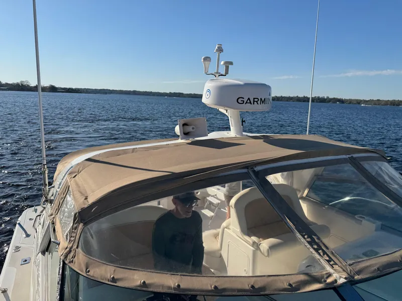 Slide: The Image of 1997 Sea Ray 370 Express Cruiser on a lake, featuring Garmin equipment and beige canopy. - 47
