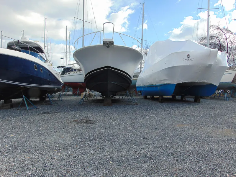 Slide: The Image of 2000 Luhrs T-360SX/SF boat on stands in a marina, surrounded by other vessels. - 2