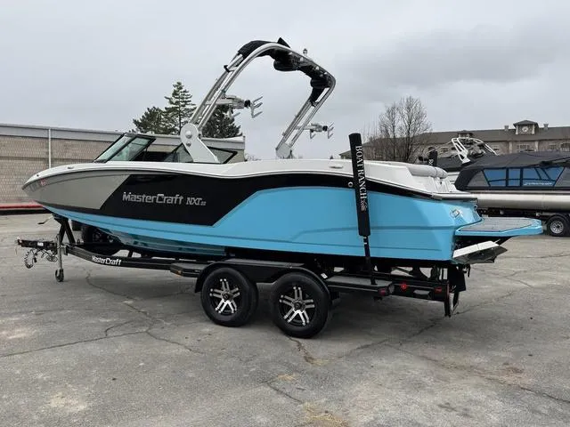 Slide: The Image of 2019 MasterCraft NXT22 boat on trailer, blue and white design, parked outdoors. - 3