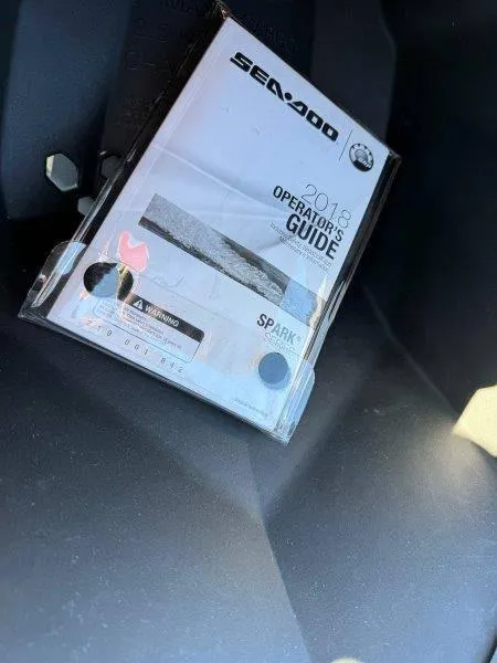 Slide: The Image of 2018 Sea-Doo Spark 3up operator's guide in vehicle compartment. - 4