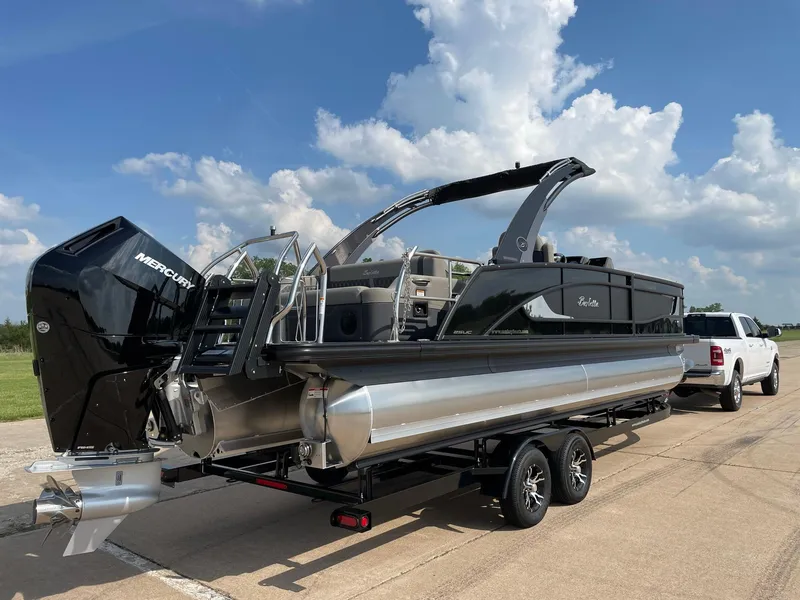 Slide: The Image of 2023 Barletta Lusso 25UCA pontoon boat on trailer, parked outdoors. - 13