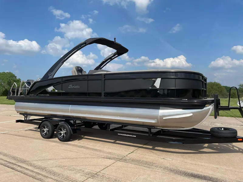 Slide: The Image of 2023 Barletta Lusso 25UCA pontoon boat on trailer under blue sky. - 15
