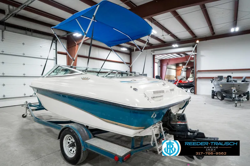 Slide: The Image of 1995 Crownline 182 BR boat with blue canopy on trailer in indoor storage. - 10