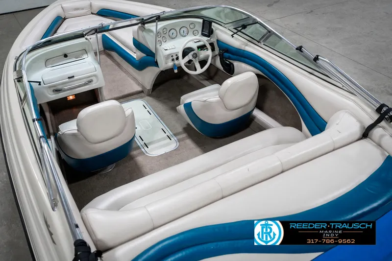 Slide: The Image of 1995 Crownline 182 BR boat interior with white and blue seating, steering wheel, and dashboard. - 15