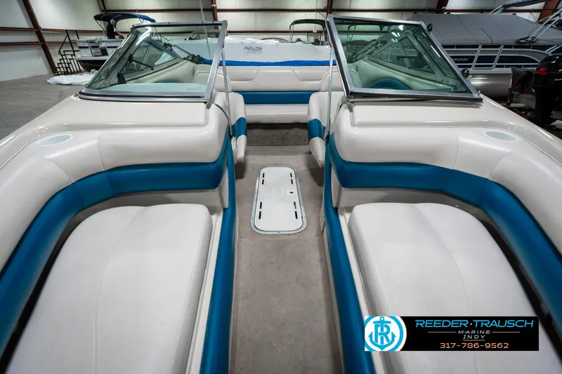 Slide: The Image of 1995 Crownline 182 BR boat interior with blue and white seating in a showroom. - 19