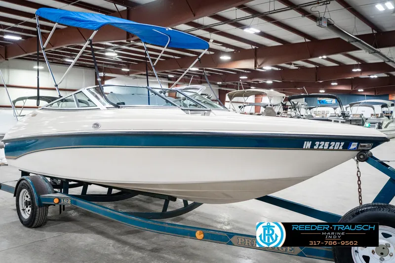Slide: The Image of 1995 Crownline 182 BR boat with blue canopy on trailer in indoor showroom. - 6