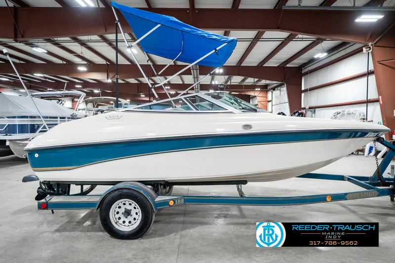 Slide: The Image of 1995 Crownline 182 BR boat with blue canopy on trailer in indoor showroom. - 7