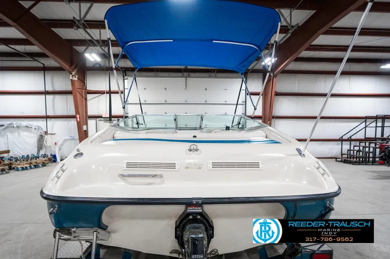 Slide: The Image of 1995 Crownline 182 BR boat with blue canopy in a warehouse setting. - 9