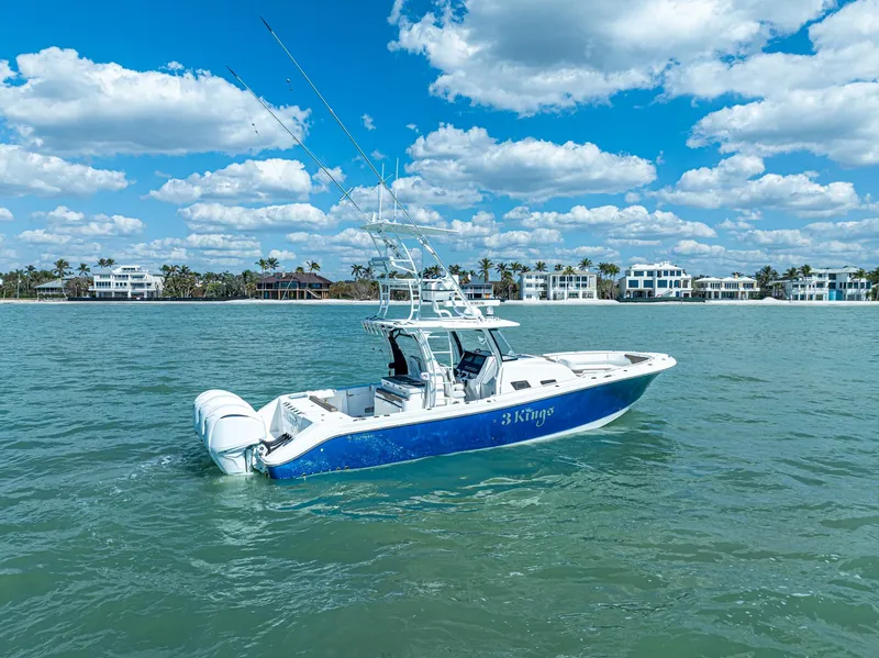 Slide: The Image of 2023 Edgewater 370CC boat on calm water under a blue sky with clouds. - 0