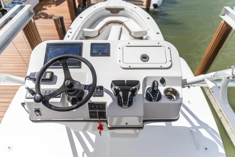 Slide: The Image of Edgewater 370CC 2023 boat helm with steering wheel and controls, docked by the water. - 13