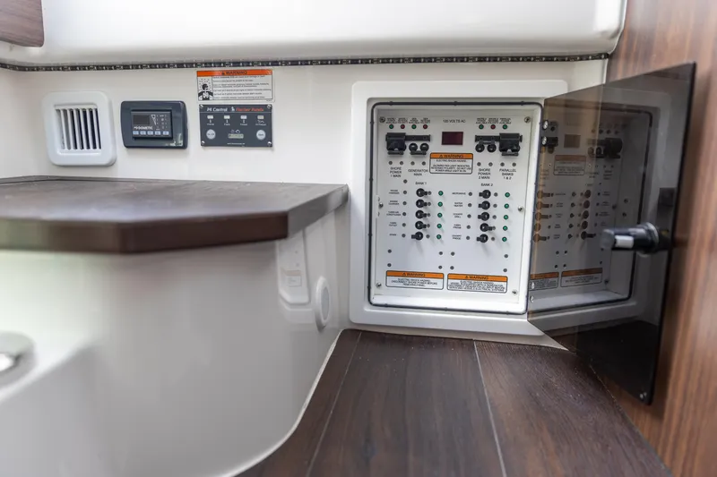 Slide: The Image of 2023 Edgewater 370CC electrical panel with control switches and wooden interior. - 18