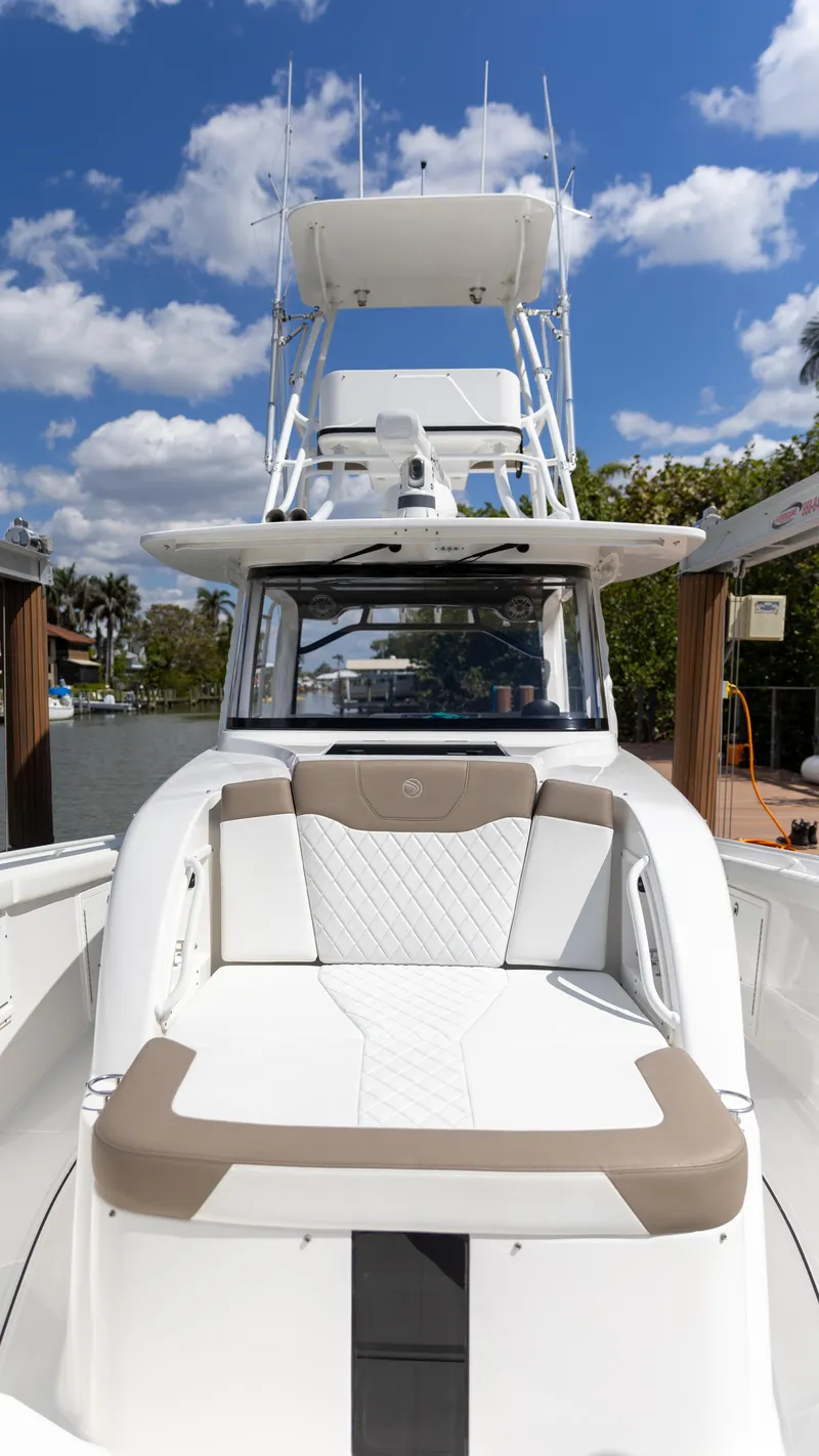Slide: The Image of 2023 Edgewater 370CC boat with sleek seating, under a bright blue sky. - 30